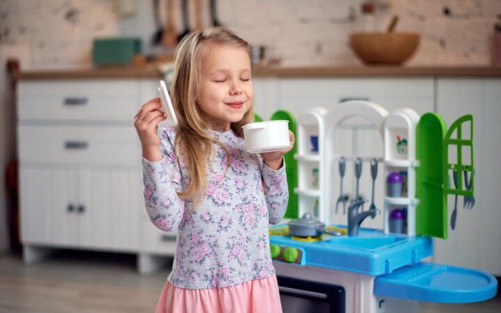 Enfant préparant une recette imaginaire dans une cuisine miniature lors d'une activité de jeu symbolique.